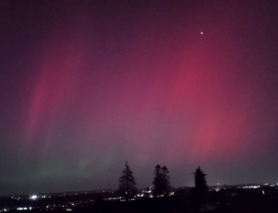 big bright magenta aurora over a distant city skyline.