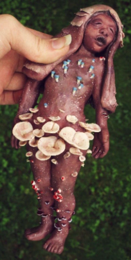 a brown painted humanoid sulpture with mushroom accents