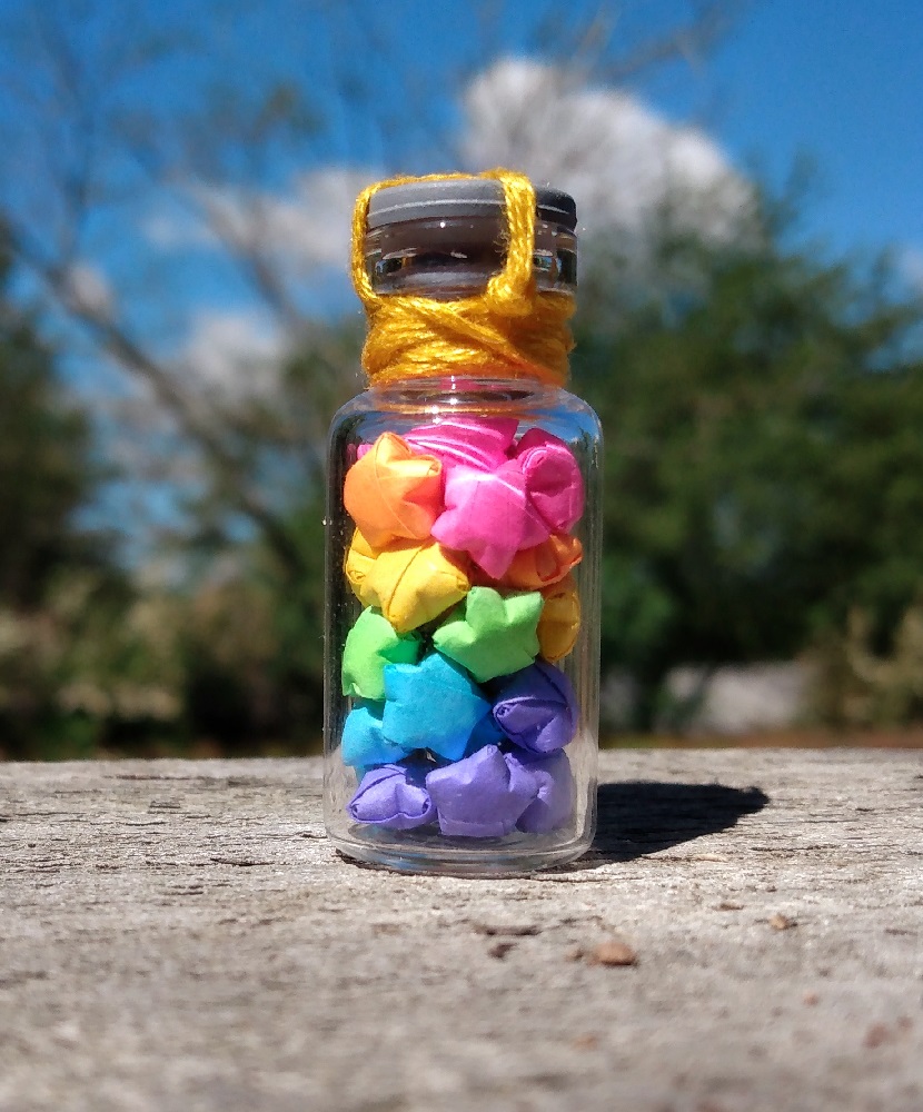 a small vial filled with rainbow colored paper stars