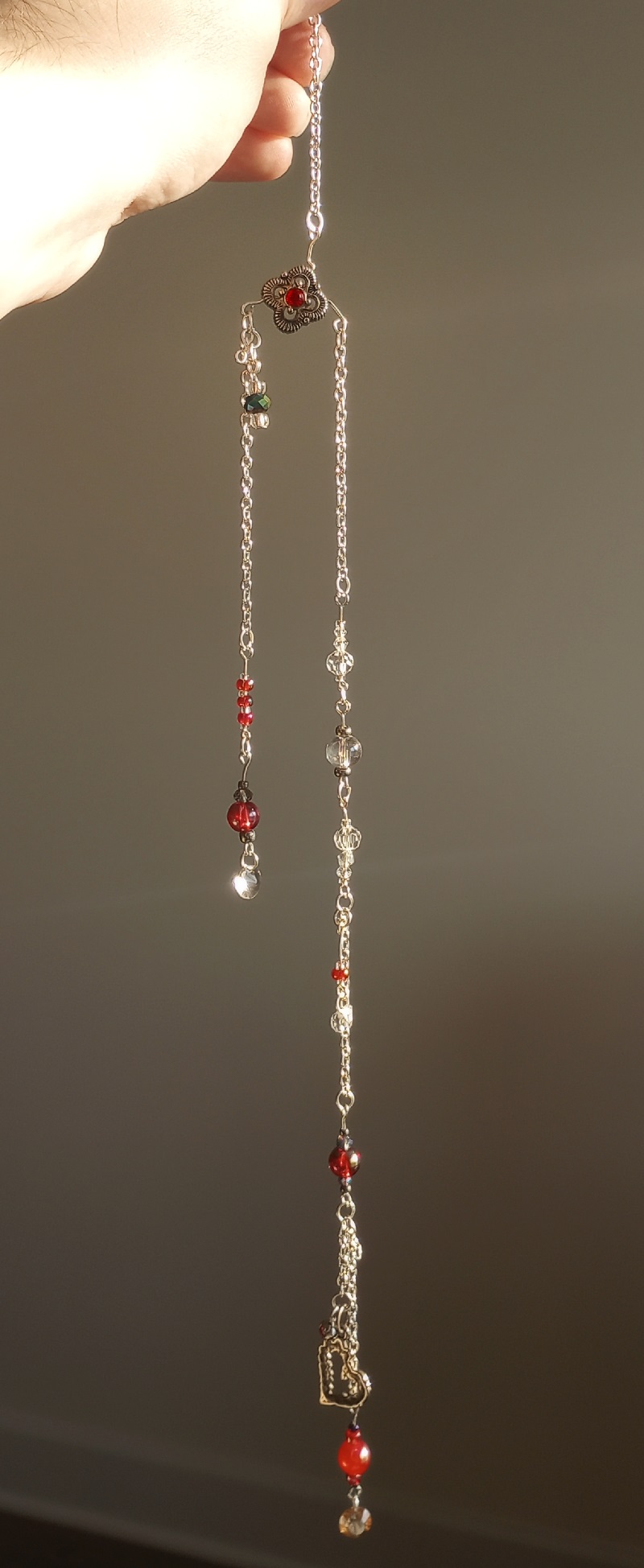 red themed sun catcher with with two dangles, the longer having a metal heart
