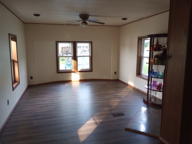 The same living room with vinyl plank floor and redish wood trim.