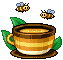 brown and yellow ceramic teacup holding honey, attracting two bees.