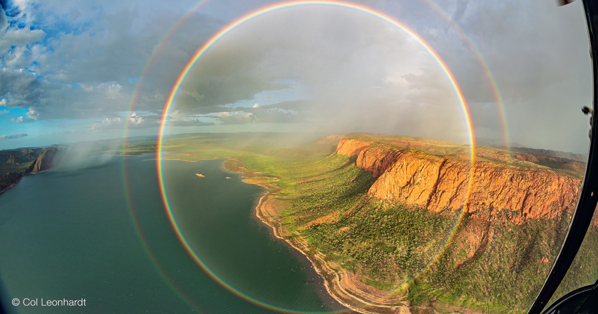 Full rainbow and secondary viewed against a shoreline and plateau