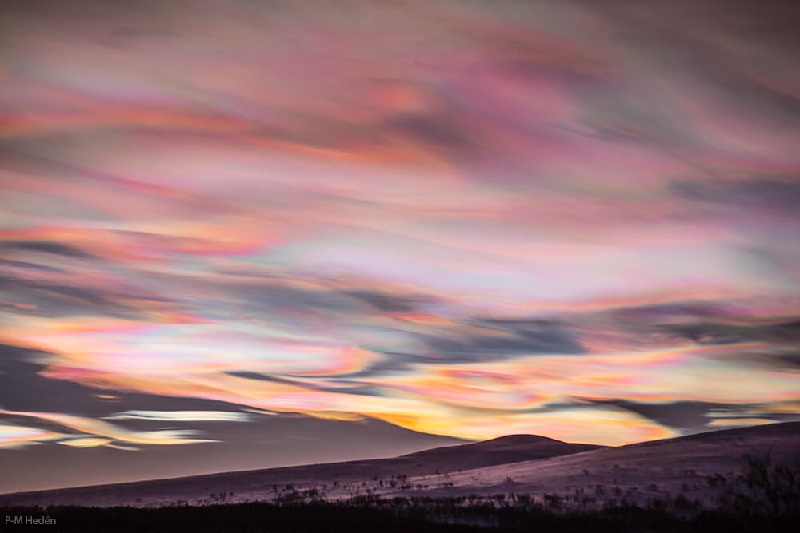 smooth bright wavy clouds blanketing a dark sky, shining with peach, gold, and a little cyan